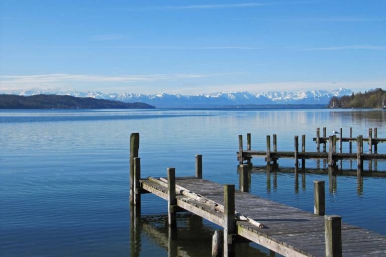 Three wooden jetties at Starnberger See in the Five Lake Region of Munich with the Alps in the background.