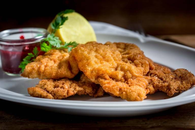 Wiener Schnitzel with lemon and cranberries arranged on a plate at the restaurant Donisl in Munich.