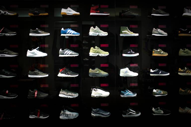 Mehrere Turnschuhe stehen nebeneinander vor einer schwarzen Wand in einem Geschäft in München.