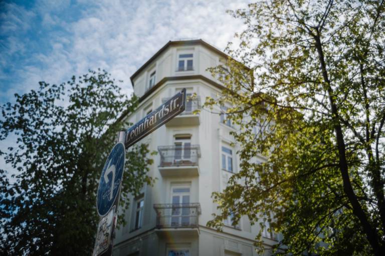 Widok niebieskiego znaku ulicznego Leonhardstraße w Haidhausen z białym domem w tle.