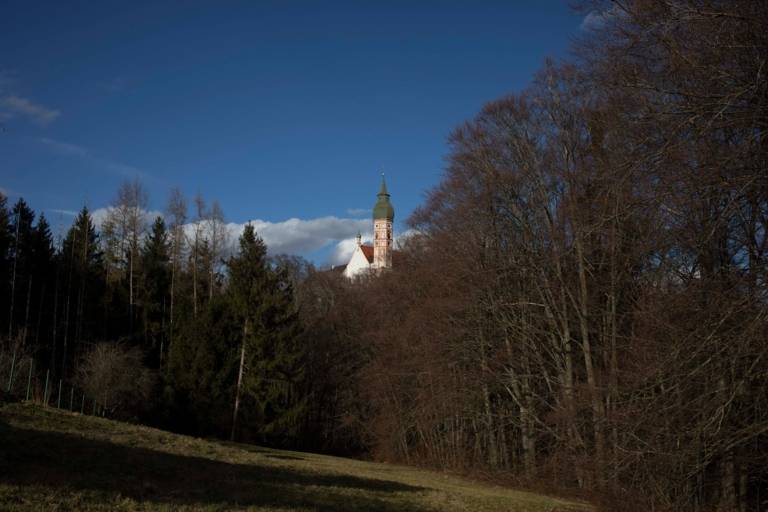 Der Kirchturm vom Kloster Andechs ragt durch die Bäume hindurch