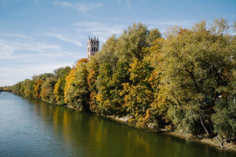 Blick auf die Isar und Sankt Maximilian in München während des Herbst.
