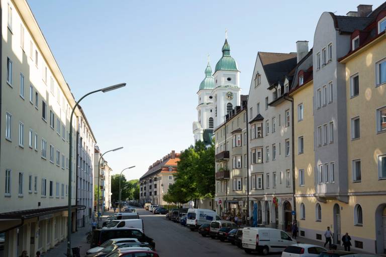 Eine Straße in Giesing mit Wohnhäusern und einer Kirche