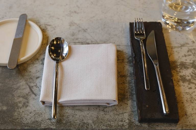 Nahaufnahme von einem Gedeck mit Besteck, Serviette und Wasserglas in einem Münchner Restaurant.