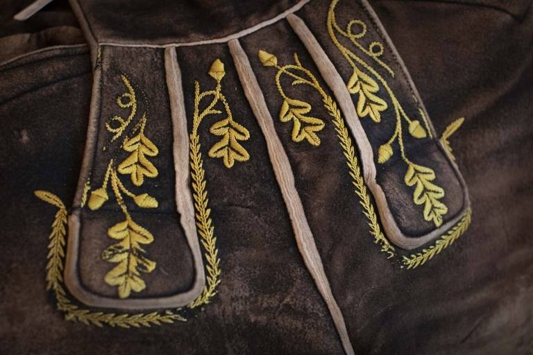 Close-up of brown leather trousers with yellow embroidery.