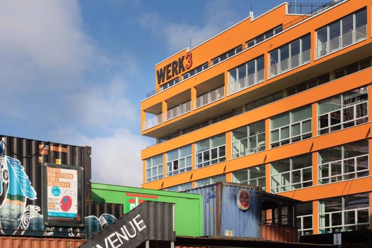 The orange exterior façade of Plant 3 with a view of colorful containers.