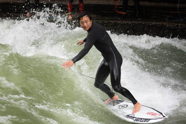 Tao Schirrmacher surft im Wetsuit auf der Eisbachwelle