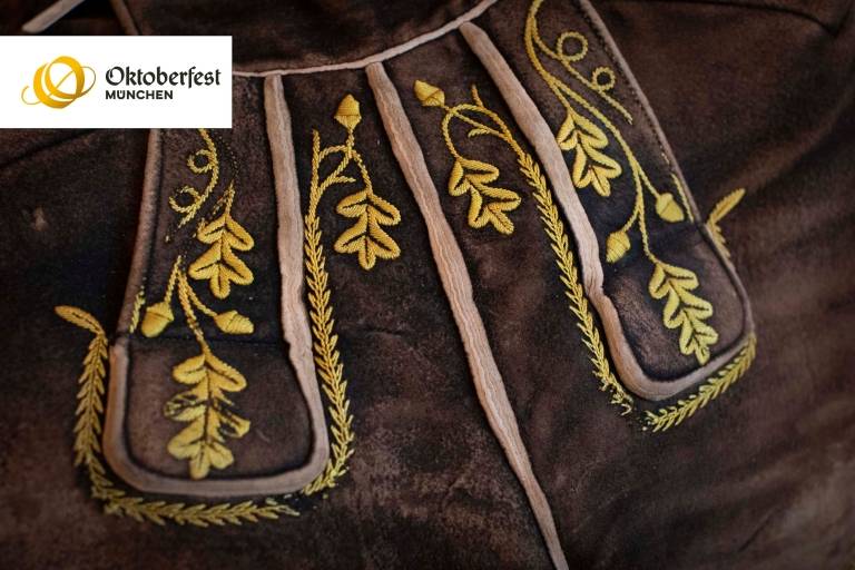 Detailaufnahme einer braunen Lederhose mit gelber Stickerei.