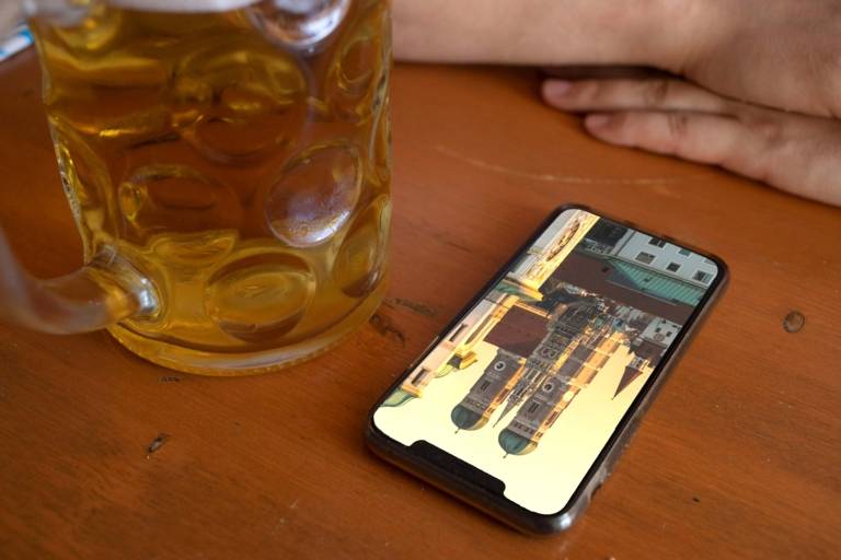 Ein Smartphone liegt auf einem Biertisch neben einer Maß Bier