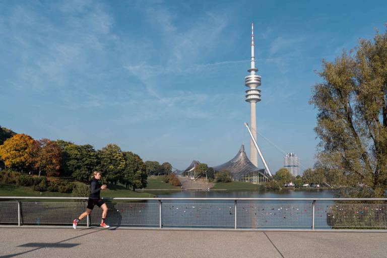 Eine Läuferin vor dem Hintergrund des Olympiaturms im Olympiapark München