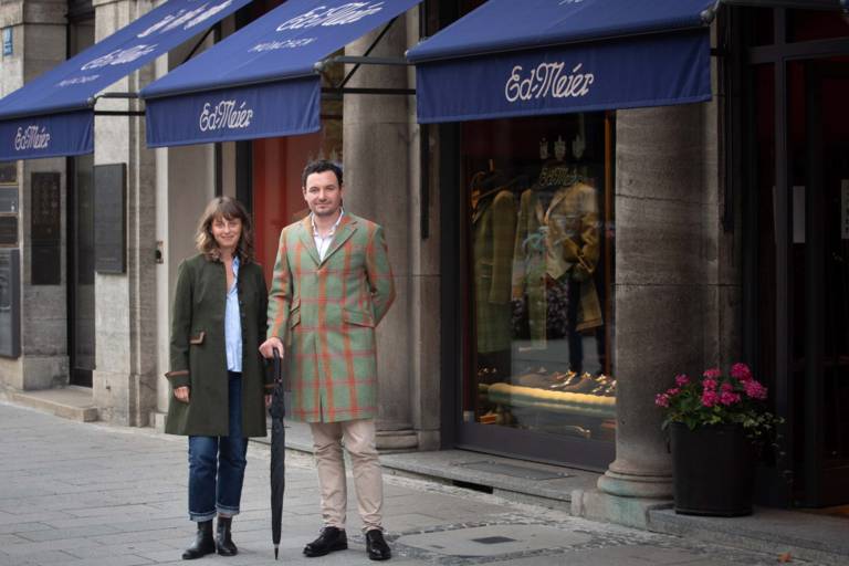 Eine Frau und ein Mann im Mantel vor dem Laden von Eduard Meier in München