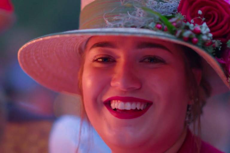 A smiling young woman with a hat at the Kocherlball in Munich