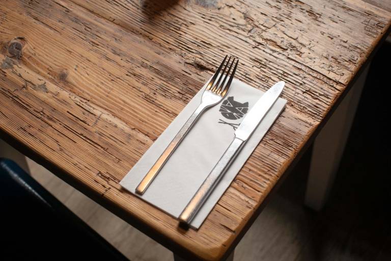 Besteck mit einer Serviette auf dem das Logo des Restaurants La katz bedruckt ist.