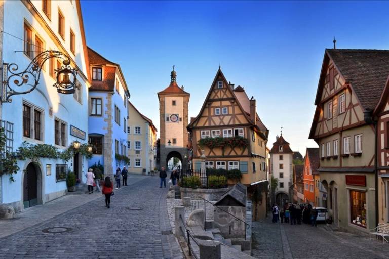 Many colourful houses on two pavements with a few people in Rothenburg ob der Tauber.